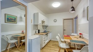 A compact kitchen with white cabinets, a wooden countertop, and a refrigerator. There is a dining table with chairs and a clock on the wall. - Jantar 2BR Apartment in Central Novo Mesto, Novo mesto, Slovenia (Novo mesto)