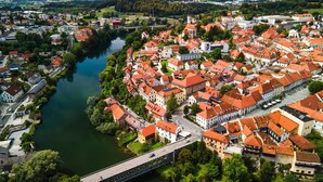 An aerial view of a town with a river, red-roofed buildings, and a bridge. - Jantar 2BR Apartment in Central Novo Mesto, Novo mesto, Slovenia (Novo mesto)