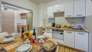 A modern kitchen with white cabinets, a sink, and a dining area with a table set for two. - Jantar 2BR Apartment in Central Novo Mesto, Novo mesto, Slovenia (Novo mesto)