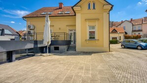 Un bâtiment jaune avec un toit en tuiles, un escalier et une voiture garée à proximité.