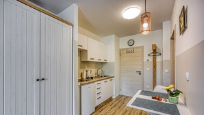 Een kleine keuken met witte kastjes, een houten aanrecht en een zithoek met een tafel en stoelen.