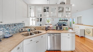 A kitchen with white cabinets, a stainless steel dishwasher, and a tiled backsplash. - Steps 2Beach~Heated Pool~Hot Tub~MiniGolf~Gameroom! (Panama City Beach)