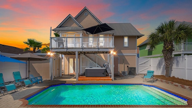 A two-story house with a swimming pool, a covered deck, and a staircase leading to an upper level. - Steps 2Beach~Heated Pool~Hot Tub~MiniGolf~Gameroom! (Panama City Beach)
