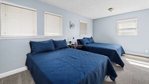 A bedroom with two beds, a nightstand, and a ceiling light.
