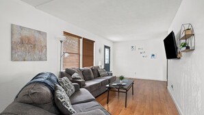 A living room with a sectional sofa, a coffee table, and a TV mounted on the wall.