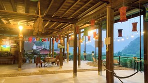 A cozy restaurant with wooden beams, hanging lanterns, and a terrace with a view of the mountains. - Duy Tuyen Ba Be Homestay Free BBQ (Ba Be)