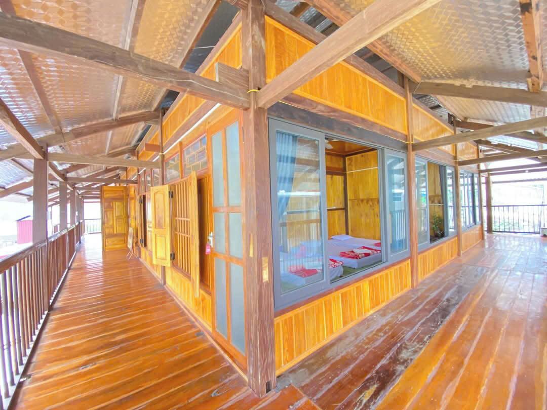 A wooden cabin with a balcony, large windows, and a wooden floor.