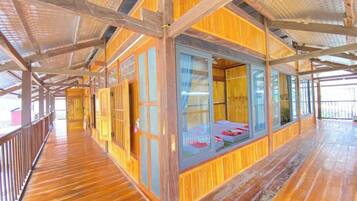 A wooden cabin with a balcony, large windows, and a wooden floor.