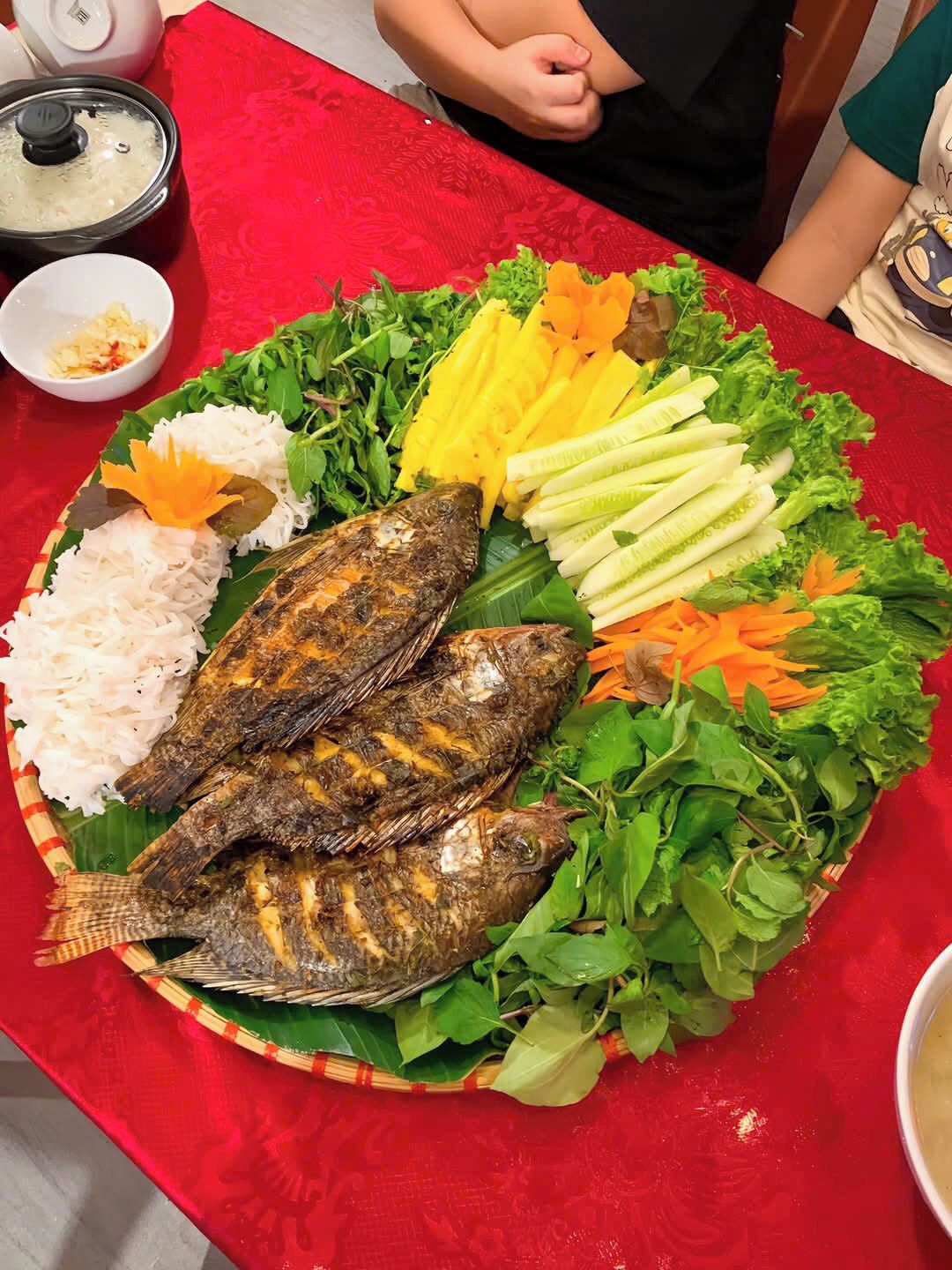 A table with grilled fish, vegetables, and rice.
