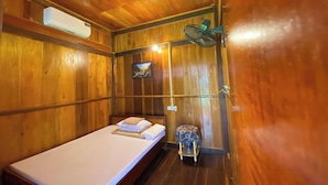 A small, wooden room with a single bed, a wall-mounted air conditioner, a small table with a water bottle, and a wall-mounted fan. - Duy Tuyen Ba Be Homestay Free BBQ (Ba Be)
