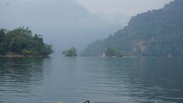 A calm river with a boat in the foreground and forested hills in the background.