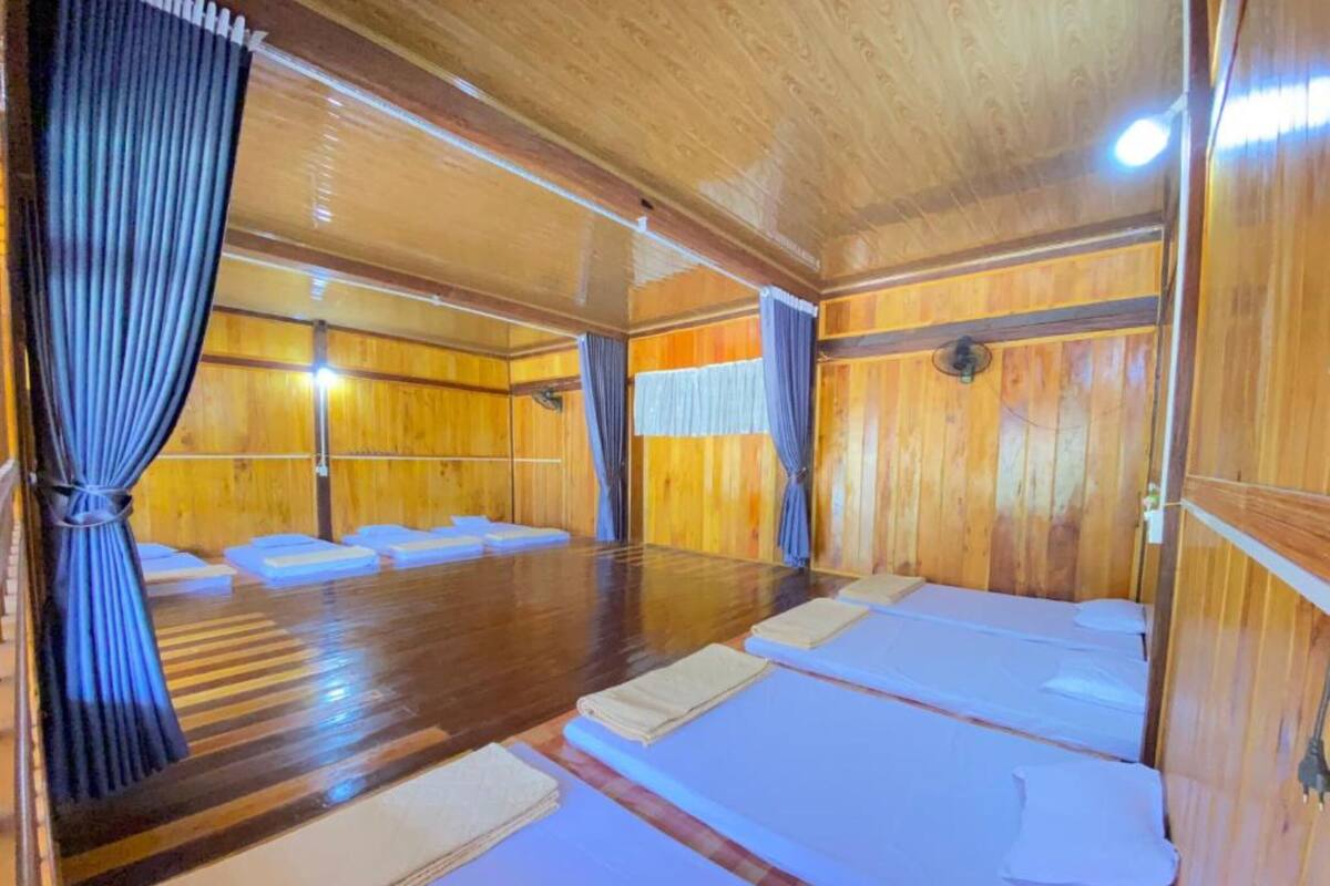 A wooden room with two beds, a wooden floor, and curtains.