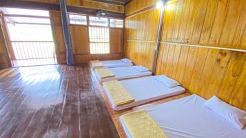 A room with wooden walls and floors, featuring four beds aligned against the wall.