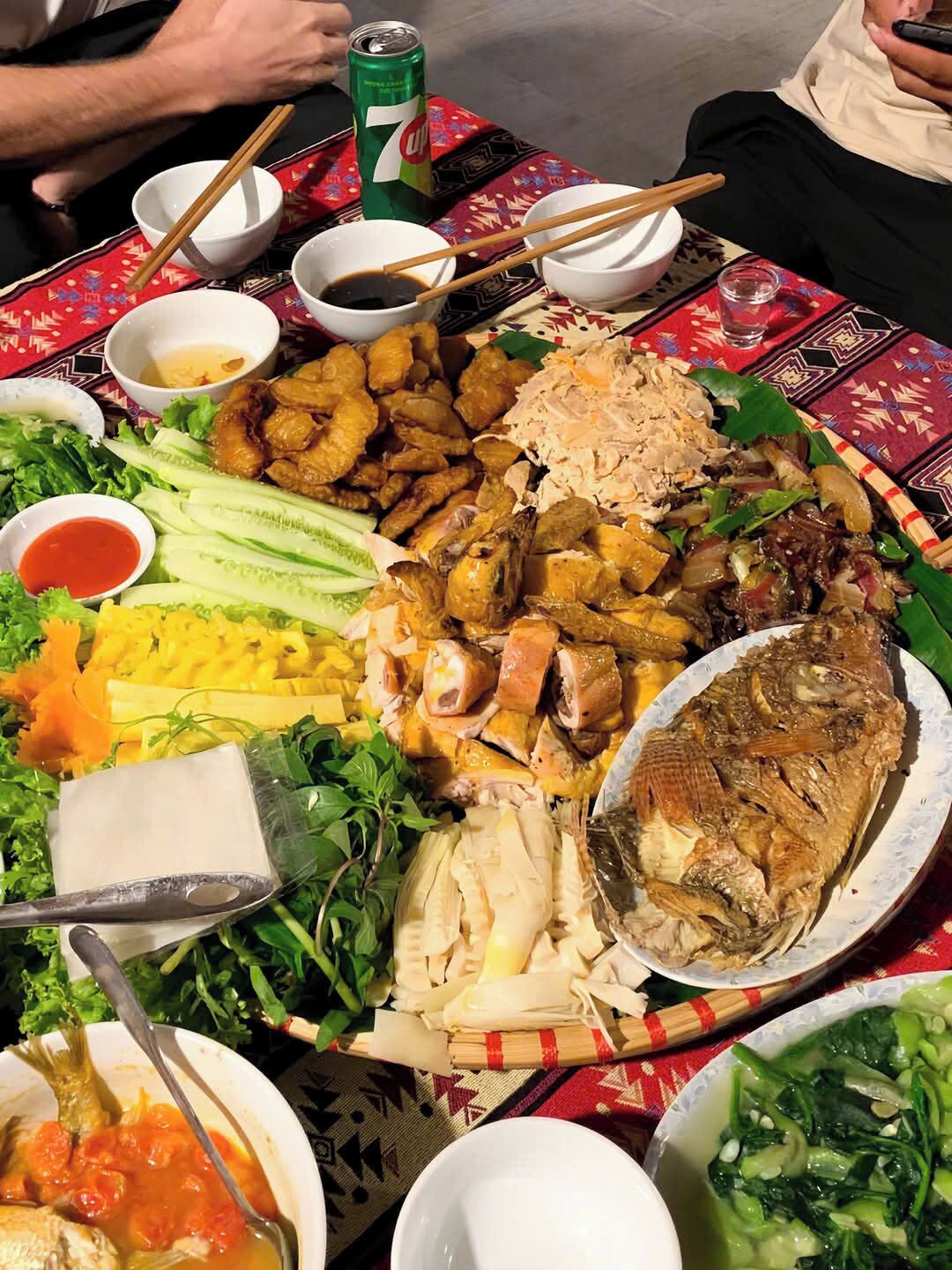 A large, round dining table with various dishes, including fried chicken, fish, and vegetables, along with several small bowls of sauces and condiments.
