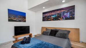 Ein modernes Schlafzimmer mit einem großen Bett, einem Flachbildfernseher und zwei Stadtansichten an den Wänden.