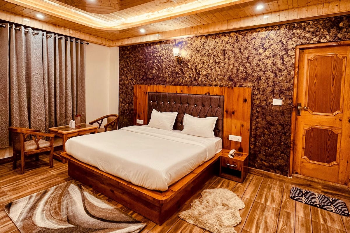 A wooden bedroom with a large bed, a nightstand, a chair, and a wardrobe.