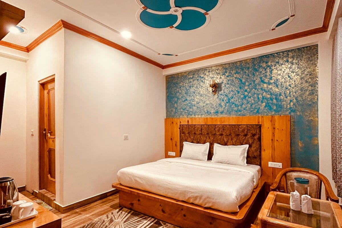 A bedroom with a wooden bed, a nightstand, a chair, a small table, and a decorative ceiling.
