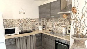 A modern kitchen with grey cabinets, a microwave, a sink, and a large vase with branches. - Double bedroom in historical Villa in perfect location (Keszthely)