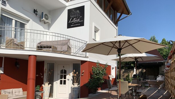 A two-story building with a balcony, outdoor seating area, and a sign indicating it is a hotel. - Double bedroom in historical Villa in perfect location (Keszthely)