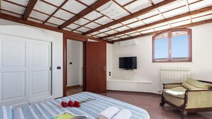 A bedroom with a bed, a wooden ceiling, a TV, a window, and a radiator. - Tenuta San Cassiano With Garden And Pool, San Cassiano, Italy (San Cassiano)