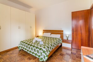 A bedroom with a bed, a wooden wardrobe, a nightstand with a lamp, and a wooden door. - Casa Gallipolina with sea view, Gallipoli, Italy (Gallipoli)
