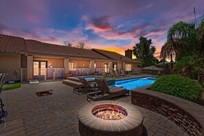 A poolside area with a fire pit, lounge chairs, and a swimming pool.