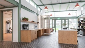 A modern kitchen with a central island, wooden cabinets, and a coffee machine. There are pendant lights above the island and a large window providing natural light. - The Lookout by Dublin At Home (Dublin)
