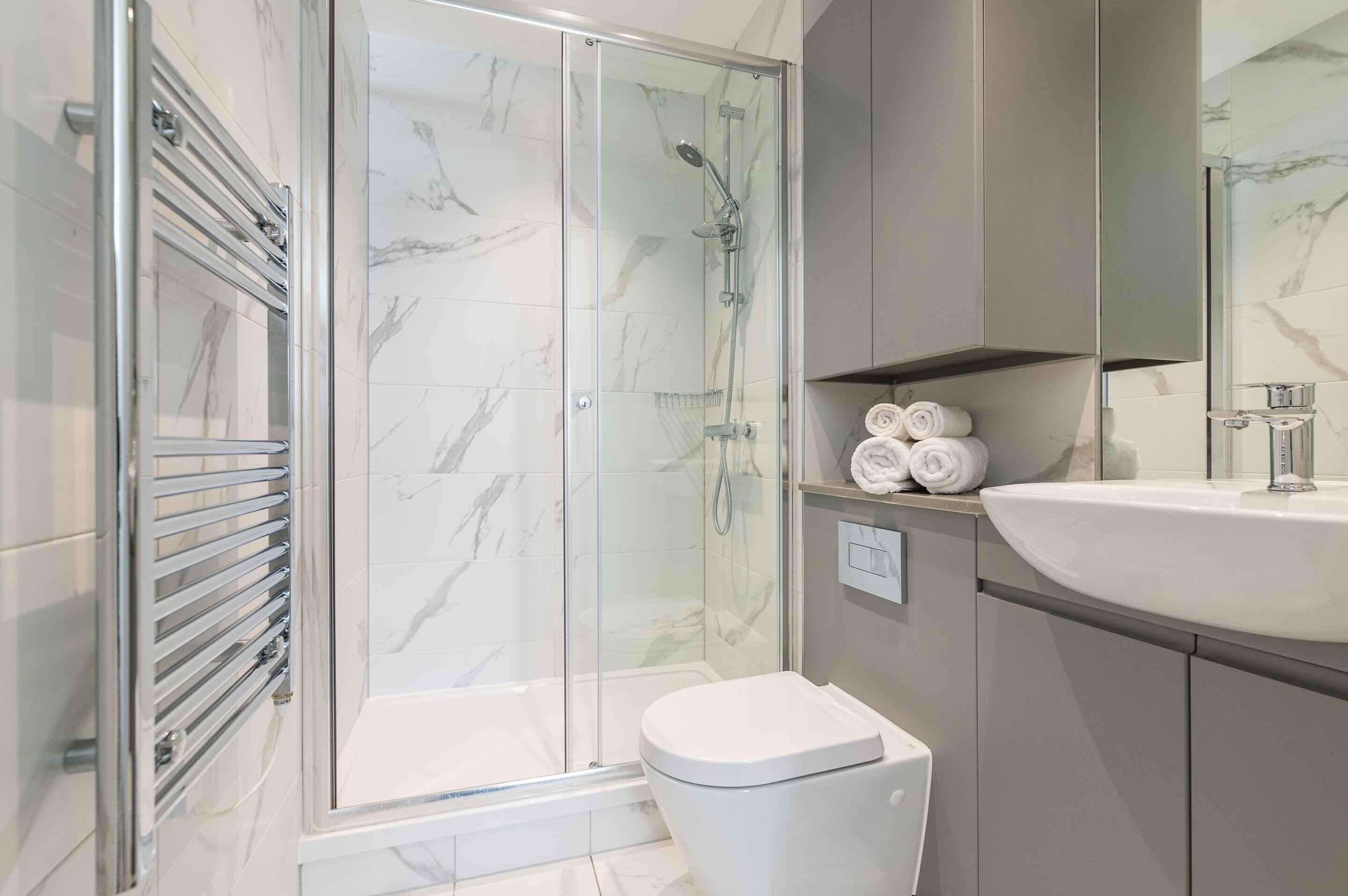 Une salle de bain moderne avec une douche à parois de verre, des toilettes blanches et un lavabo avec un miroir au-dessus.