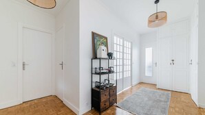 A hallway with wooden flooring, white walls, a gray rug, a black shelf with toys, and a hanging light fixture. - 3 pieces Arc de triomphe Champs Elysée - Paris 16 (Paris)