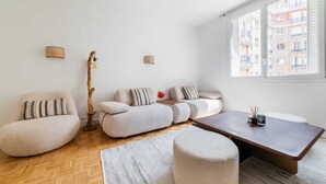 A modern living room with a sofa set, a wooden floor, and a large window with a view of buildings. - 3 pieces Arc de triomphe Champs Elysée - Paris 16 (Paris)