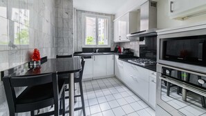 A modern kitchen with white cabinets, a black countertop, and a built-in oven. - 3 pieces Arc de triomphe Champs Elysée - Paris 16 (Paris)