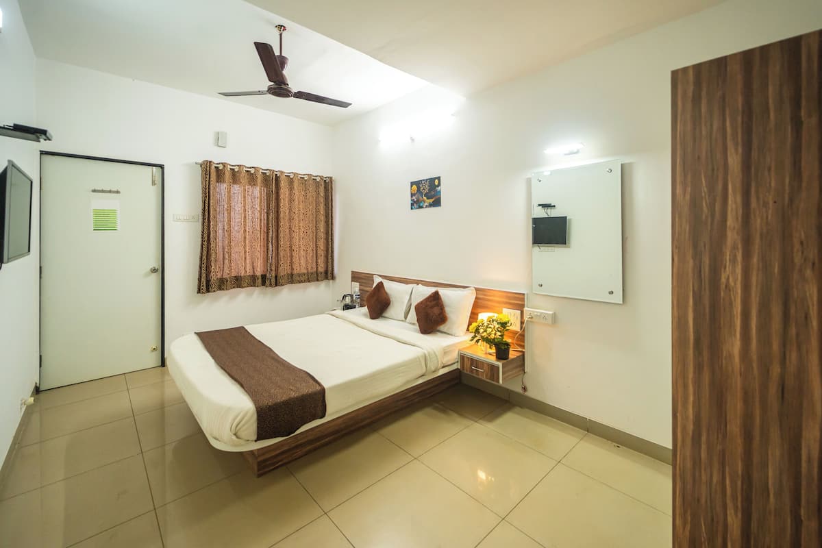 A bedroom with a bed, a nightstand, a ceiling fan, a door, and a mirror.