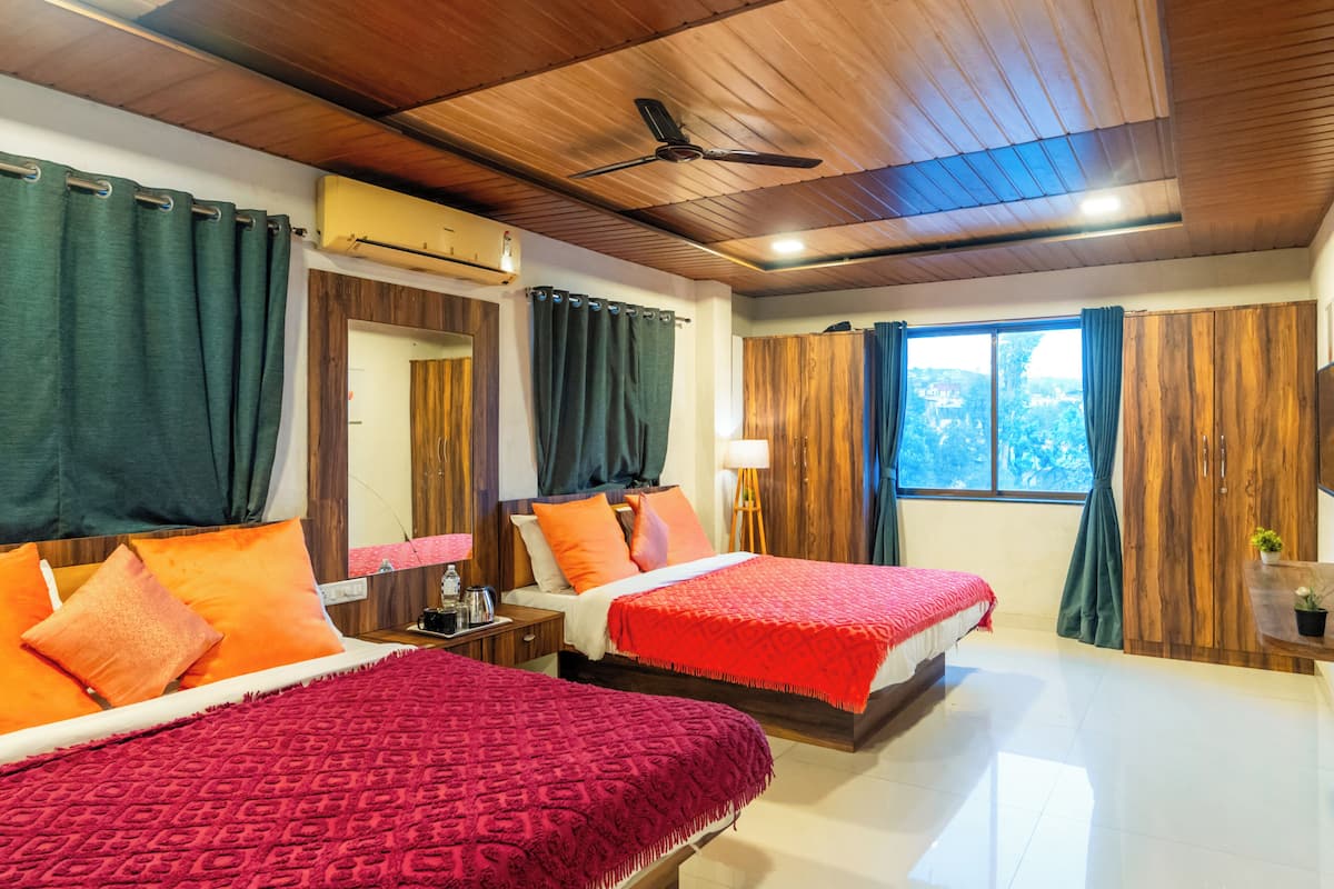 A hotel room with two beds, a ceiling fan, a window with curtains, and a view of the outside.