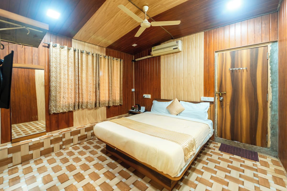 A wooden-paneled bedroom with a bed, curtains, a ceiling fan, and an air conditioning unit.