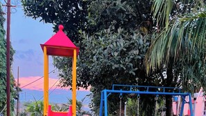 A playground with a red slide and blue swings. - Strawberry County (Mahabaleshwar)