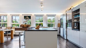 Eine moderne Küche mit weißen Schränken, einer zentralen Kochinsel und einem Essbereich mit Holztisch und Stühlen.