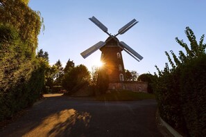 A windmill with four sails, a brick tower, and a clear sky.