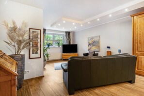 Ein modernes Wohnzimmer mit Sofa, Fernseher und Kunstwerk an der Wand.