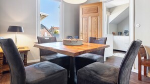 Ein Essbereich mit einem Holztisch, vier Stühlen, einer Lampe und Blick ins Freie.