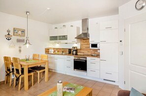 Una cocina moderna con armarios blancos, una mesa de comedor de madera y sillas.