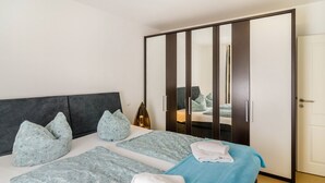 A double bed with a dark headboard, two pillows, a bedside table with a lamp, and a large mirror.