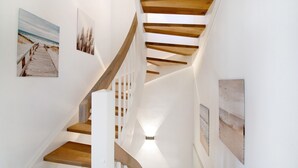 Un escalier en colimaçon avec des marches en bois et des rampes blanches, menant à l’étage supérieur.