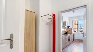 Uma cozinha moderna com armários de madeira, uma porta vermelha e vista para a cidade através de uma janela.