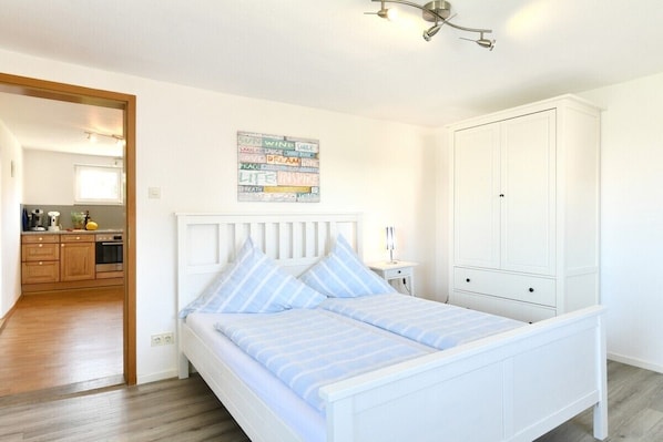 Una camera da letto con un letto, un armadio, una cucina sullo sfondo e un poster motivazionale al muro.