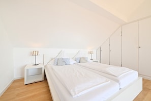 A bedroom with a bed, two bedside tables, a wardrobe, and a lamp.
