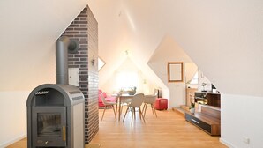 Un interior moderno con chimenea, un comedor con sillas y una escalera que sube a otro nivel.