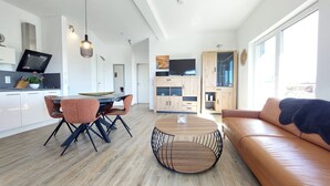 A modern kitchen with a dining area, a round coffee table, and a leather sofa.