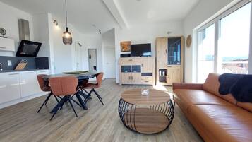 A modern kitchen with a dining area, a round coffee table, and a sofa.