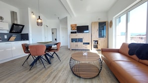 A modern kitchen with a dining area, a round coffee table, and a sofa.