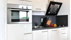 A modern kitchen with a built-in oven, a black range hood, a sink, and a countertop with kitchen utensils.